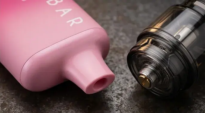 Unnamed vape device in pink shown next to black tank atomizer on gray surface